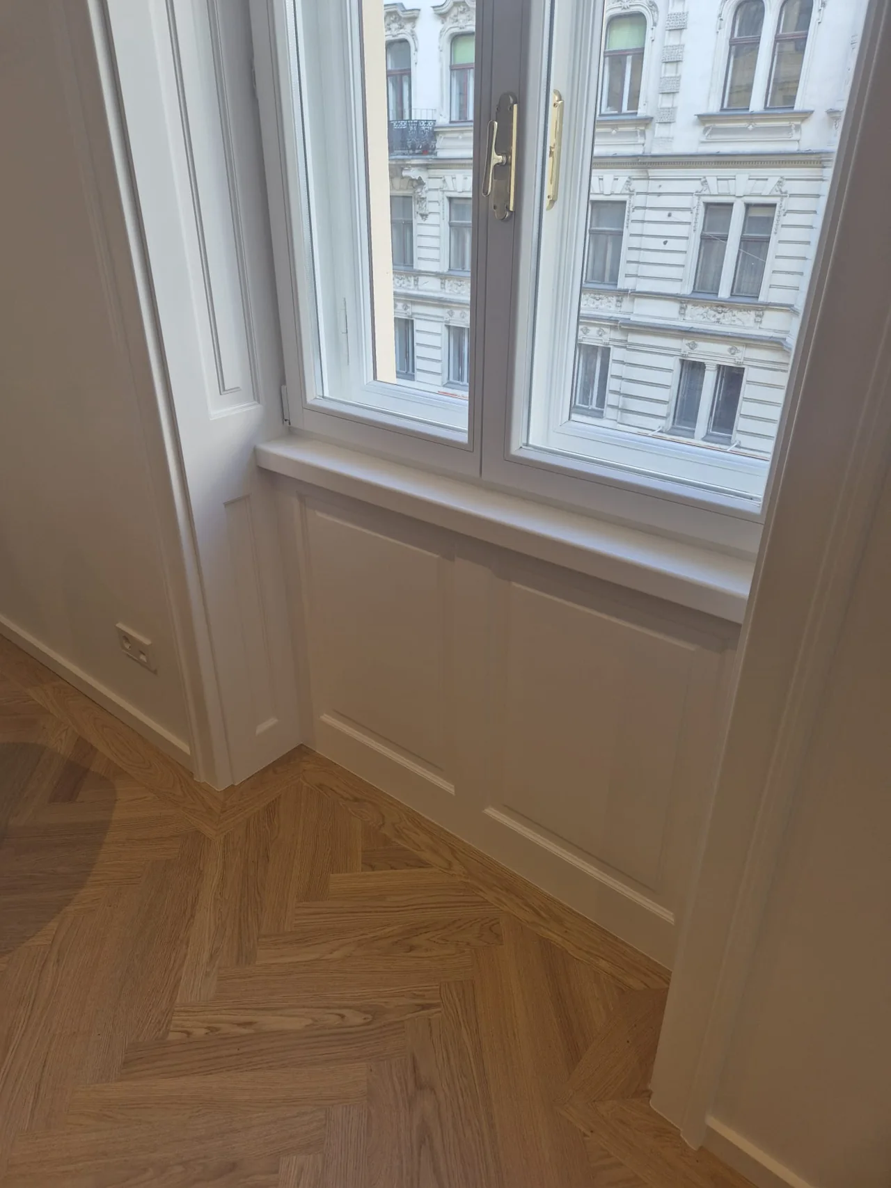 Sanierter Altbau mit weißen Fenstern und Fischgrätparkett